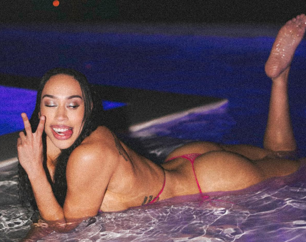 Dearica Hamby Laying down in a pool in a red thong